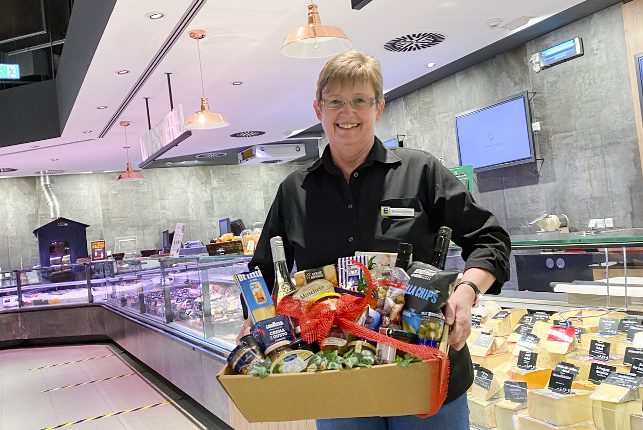 Käsetheke und Verkäufer mit Geschenkkorb